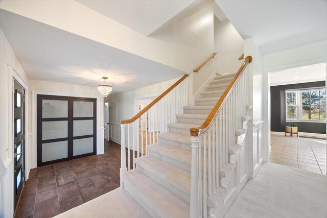 foyer featuring an inviting chandelier, stairs, and dark tile patterned flooring