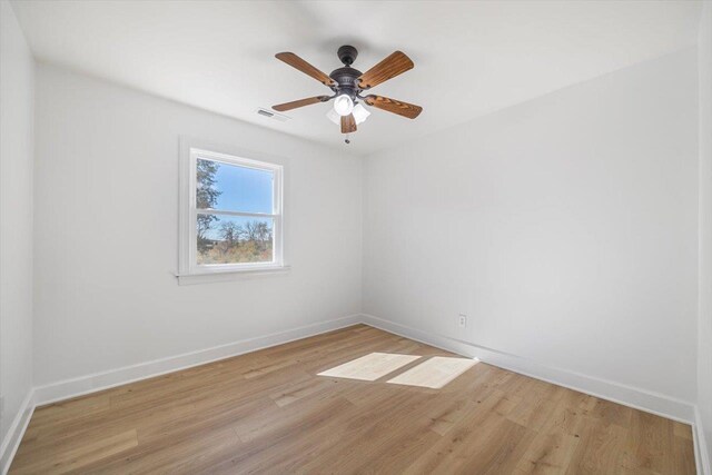 unfurnished room featuring light wood finished floors, baseboards, visible vents, and a ceiling fan