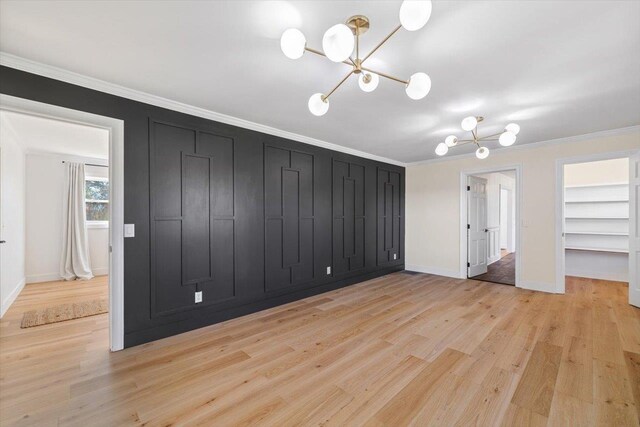 interior space with light wood-style floors, built in shelves, crown molding, and an inviting chandelier