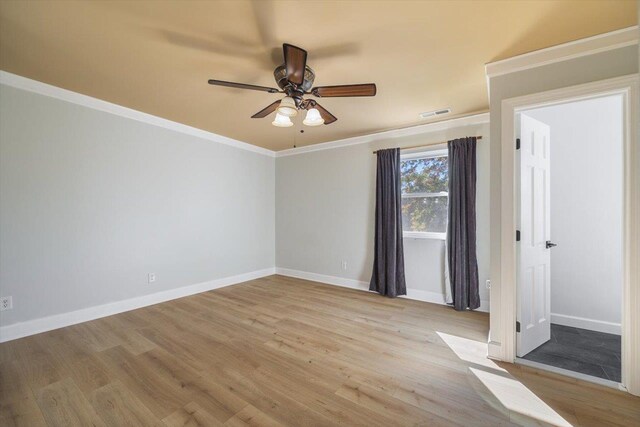 empty room featuring a ceiling fan, crown molding, light wood-style flooring, and baseboards