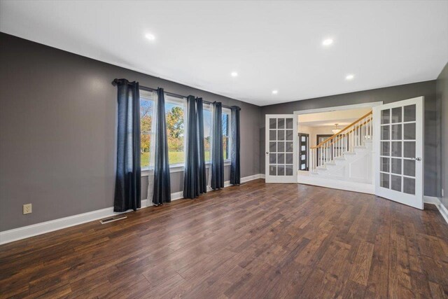 empty room with dark wood-type flooring, visible vents, baseboards, stairs, and french doors