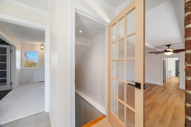 hall with light wood finished floors, crown molding, and french doors