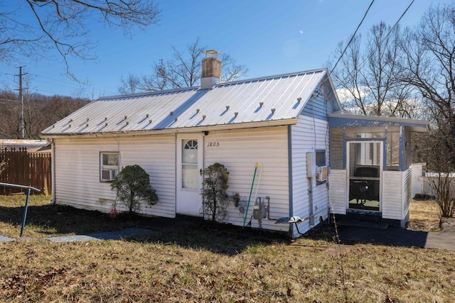 back of house with a chimney, fence, and metal roof