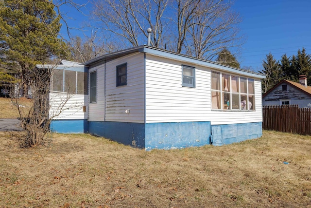 view of side of home featuring a yard, fence, and a sunroom