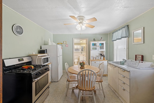 kitchen with white appliances, ceiling fan, plenty of natural light, and a textured ceiling