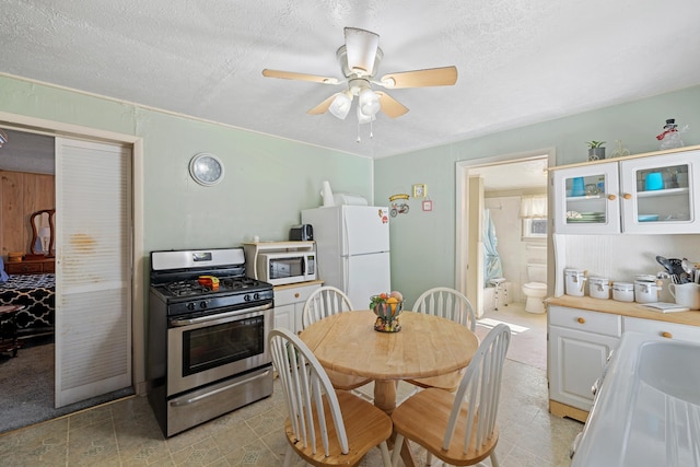 kitchen featuring a ceiling fan, freestanding refrigerator, light countertops, a textured ceiling, and stainless steel range with gas cooktop