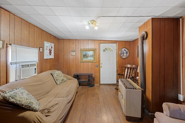 living room featuring light wood-style flooring, wooden walls, and cooling unit