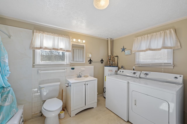 laundry room with laundry area, washer and clothes dryer, a textured ceiling, water heater, and a sink