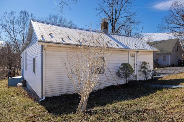 view of property exterior with metal roof and a chimney