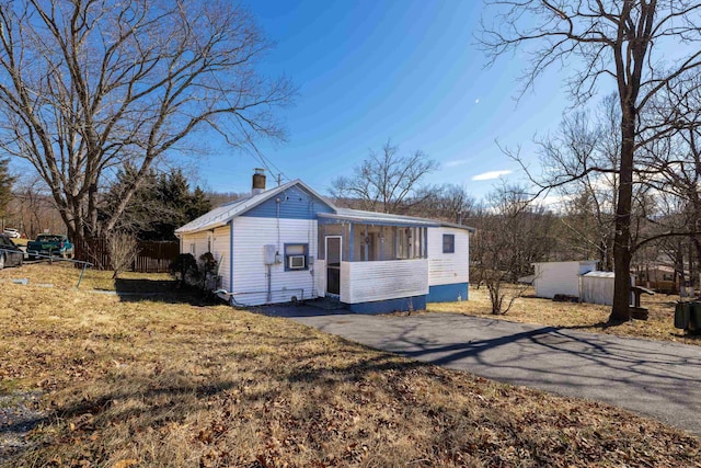 view of front of home with driveway, a chimney, a front lawn, and fence