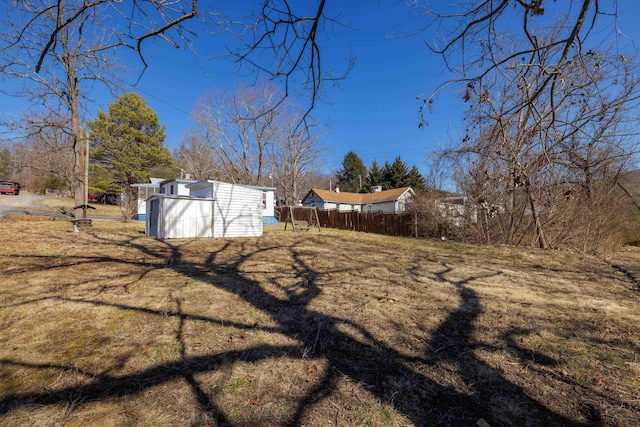 view of yard featuring fence, a storage unit, and an outbuilding