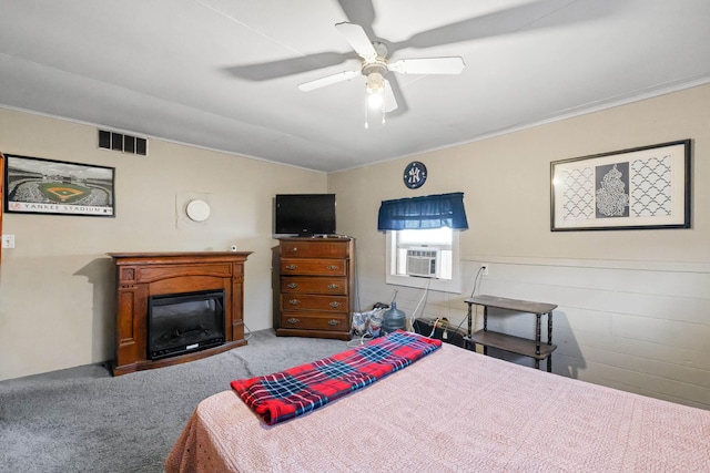 bedroom with cooling unit, visible vents, a ceiling fan, carpet, and a glass covered fireplace