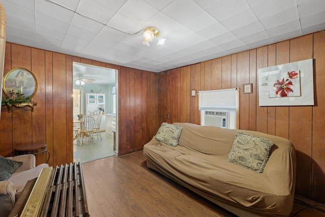 living room with cooling unit, wood finished floors, and wooden walls