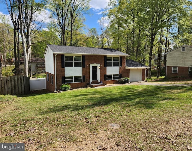 raised ranch featuring brick siding, fence, a front yard, and driveway