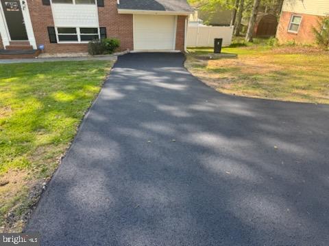 view of front of property featuring brick siding, a garage, entry steps, driveway, and a front yard