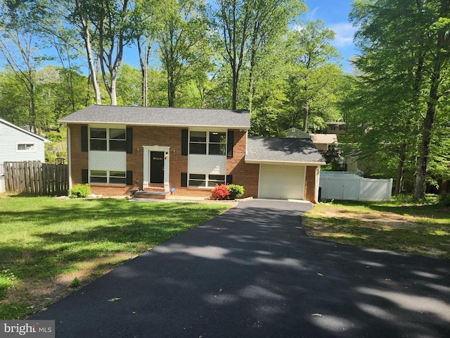 bi-level home featuring fence, aphalt driveway, and brick siding