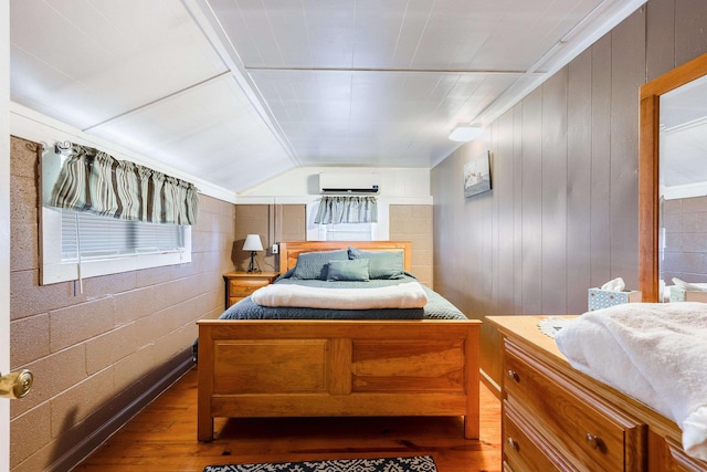 bedroom featuring lofted ceiling, a wall mounted air conditioner, and wood-type flooring