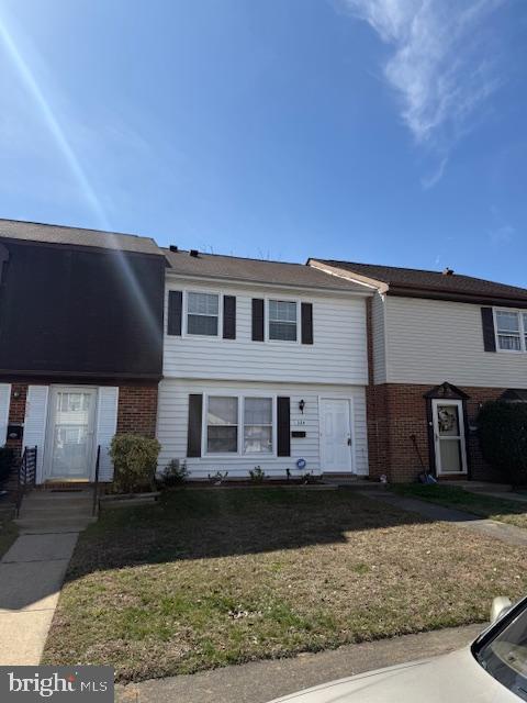 townhome / multi-family property with brick siding and a front lawn