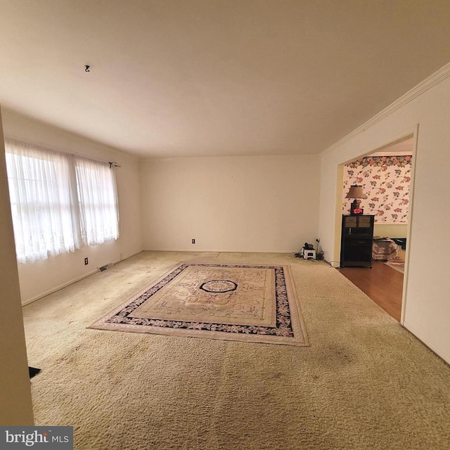 unfurnished living room with crown molding and carpet