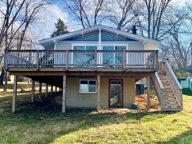 back of property with a wooden deck and a lawn