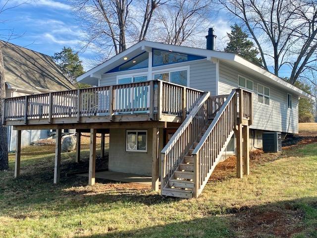 rear view of property featuring central AC unit, a deck, and a lawn