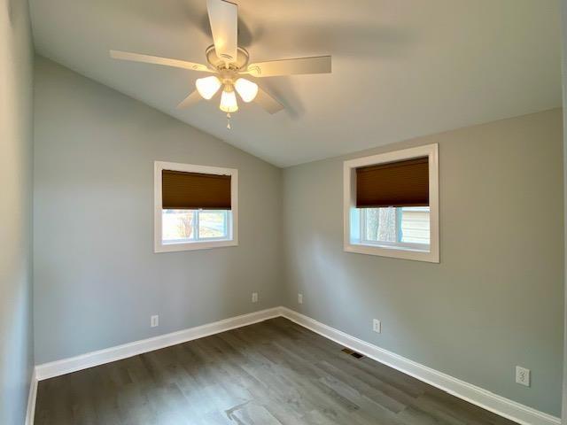 empty room featuring dark hardwood / wood-style flooring, ceiling fan, a healthy amount of sunlight, and lofted ceiling