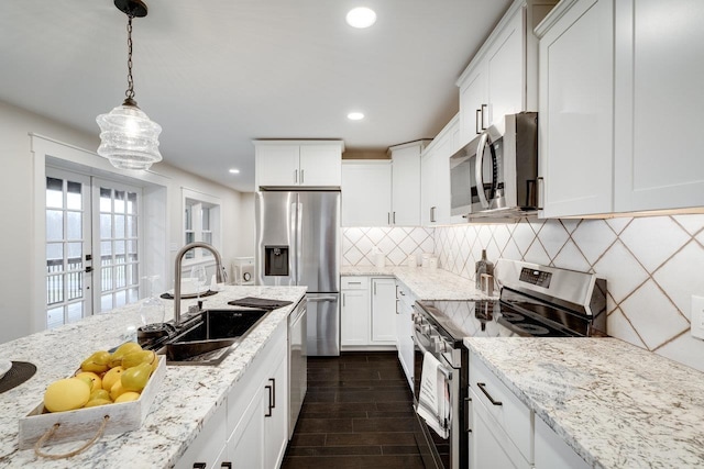 kitchen with pendant lighting, sink, white cabinetry, and appliances with stainless steel finishes