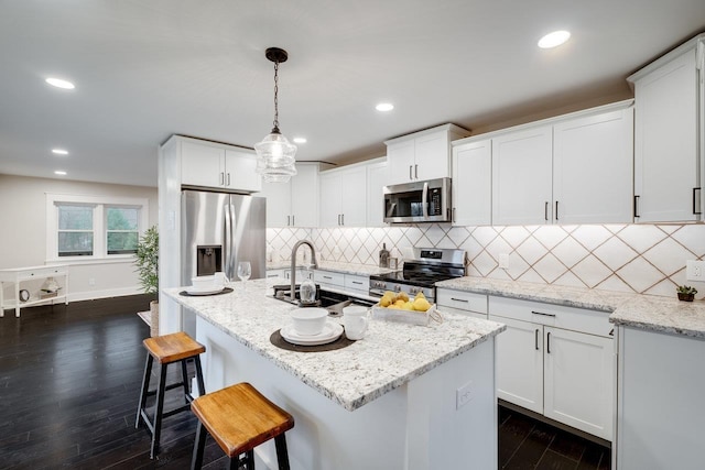 kitchen featuring white cabinetry, light stone countertops, decorative light fixtures, and stainless steel appliances