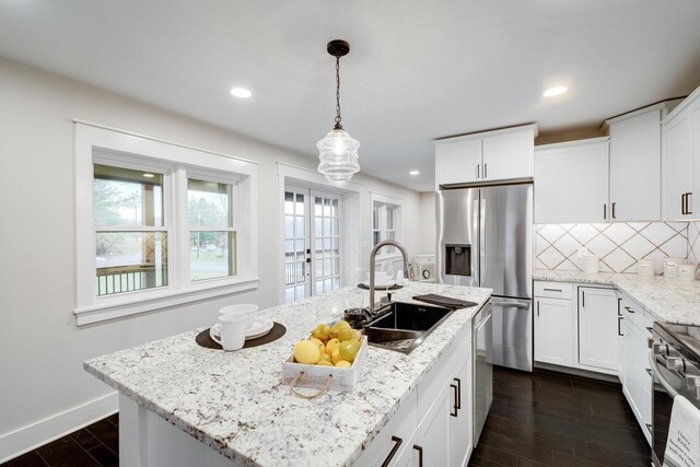 kitchen featuring white cabinetry, appliances with stainless steel finishes, a kitchen island with sink, and pendant lighting