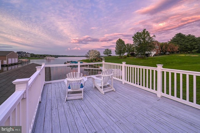 deck at dusk featuring a water view and a yard