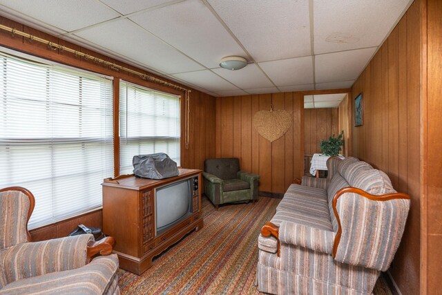 living room featuring a paneled ceiling and wood walls