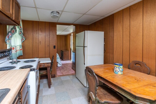 kitchen featuring a paneled ceiling, white appliances, and wood walls