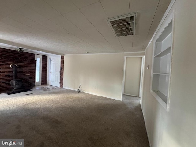 unfurnished living room featuring carpet flooring, built in features, and a wood stove