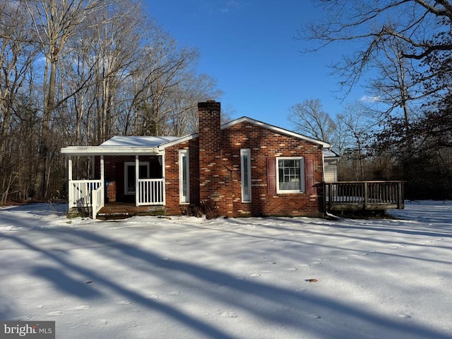 snow covered rear of property with covered porch