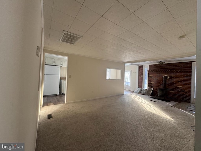 unfurnished living room featuring a wood stove and carpet flooring