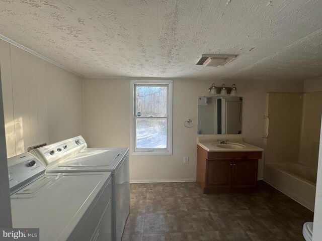 laundry room with sink, washing machine and clothes dryer, and a textured ceiling