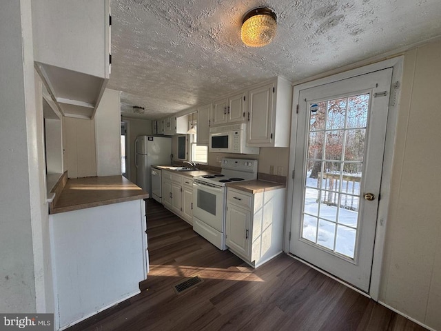 kitchen featuring white appliances, dark hardwood / wood-style flooring, and white cabinets