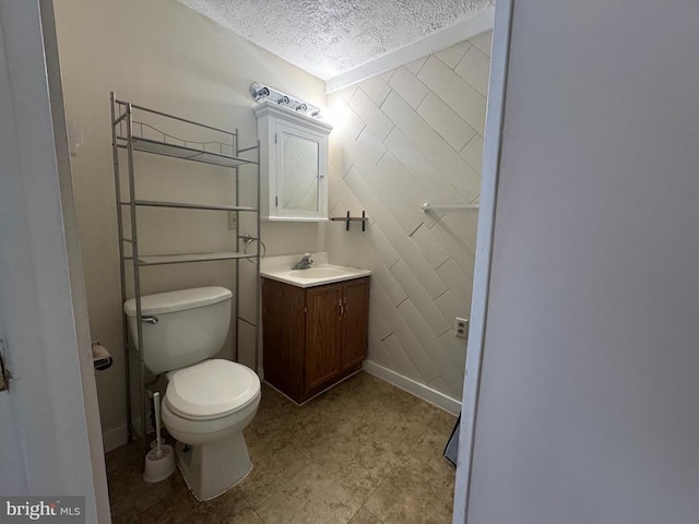 bathroom with vanity, toilet, and a textured ceiling