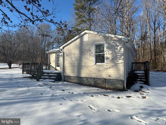 view of snowy exterior with a wooden deck