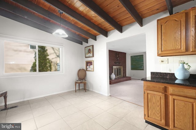 kitchen featuring wood ceiling, hanging light fixtures, a fireplace, lofted ceiling with beams, and dark stone counters