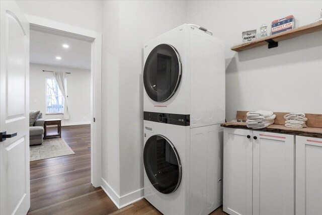 washroom with stacked washer / drying machine and dark wood-type flooring