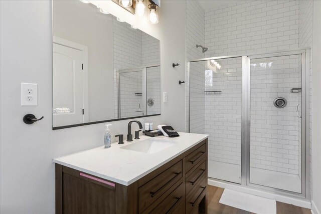 bathroom with hardwood / wood-style flooring, vanity, and an enclosed shower