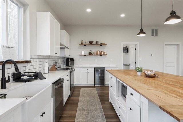 kitchen featuring pendant lighting, wine cooler, wooden counters, and white cabinets