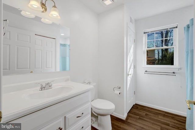 bathroom with vanity, wood finished floors, baseboards, an inviting chandelier, and toilet