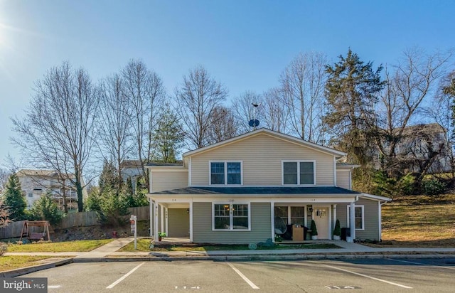 traditional-style home featuring fence, covered porch, and uncovered parking