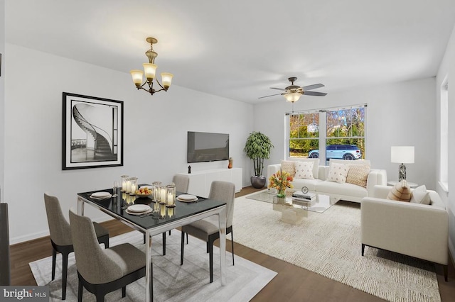 dining area featuring baseboards, dark wood-style flooring, and ceiling fan with notable chandelier