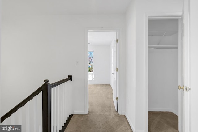 hall featuring an upstairs landing, baseboards, and carpet floors