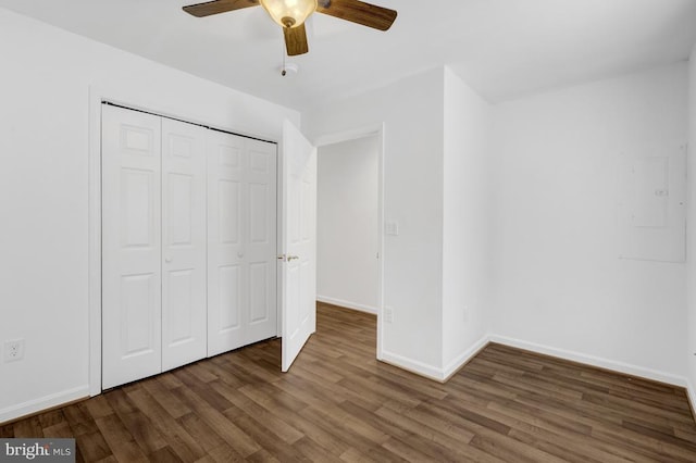 unfurnished bedroom featuring electric panel, wood finished floors, a closet, baseboards, and ceiling fan