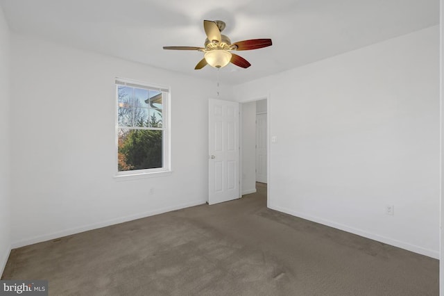 carpeted empty room with a ceiling fan and baseboards