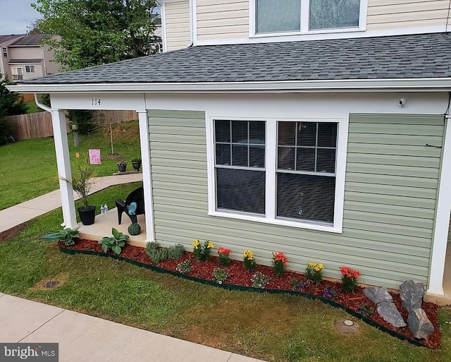 view of side of property with a lawn and roof with shingles